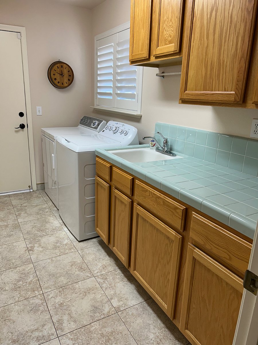 Shared laundry room with lots of counter space, sink, window with lots of natural light, full size washer, full size dryer and door that opens into garage.