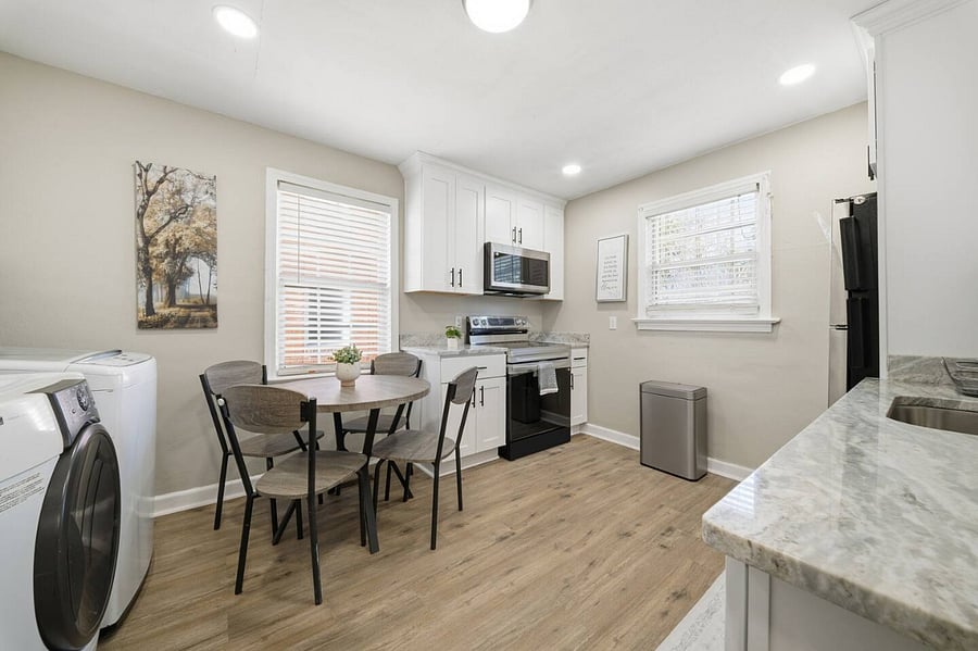 Charming dining nook beside the kitchen, perfect for shared meals or morning coffee. Bright windows, modern appliances, and open counter space create a welcoming setup for cooking and gathering.