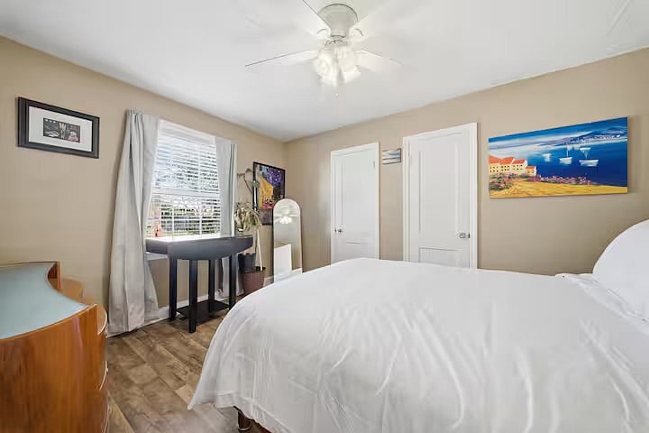 Peaceful bedroom featuring a comfortable bed with crisp linens and plenty of natural light. A small desk by the window offers a quiet spot to work or unwind, while soft tones create a relaxing retreat.