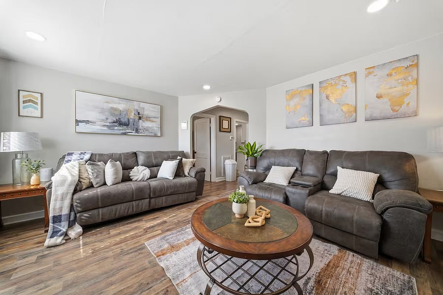 Spacious lounge area featuring two oversized sofas with plenty of seating for everyone. Thoughtful dcor, soft accent pillows, and warm wood flooring create a welcoming space perfect for conversations, game nights, or simply stretching out and relaxing.