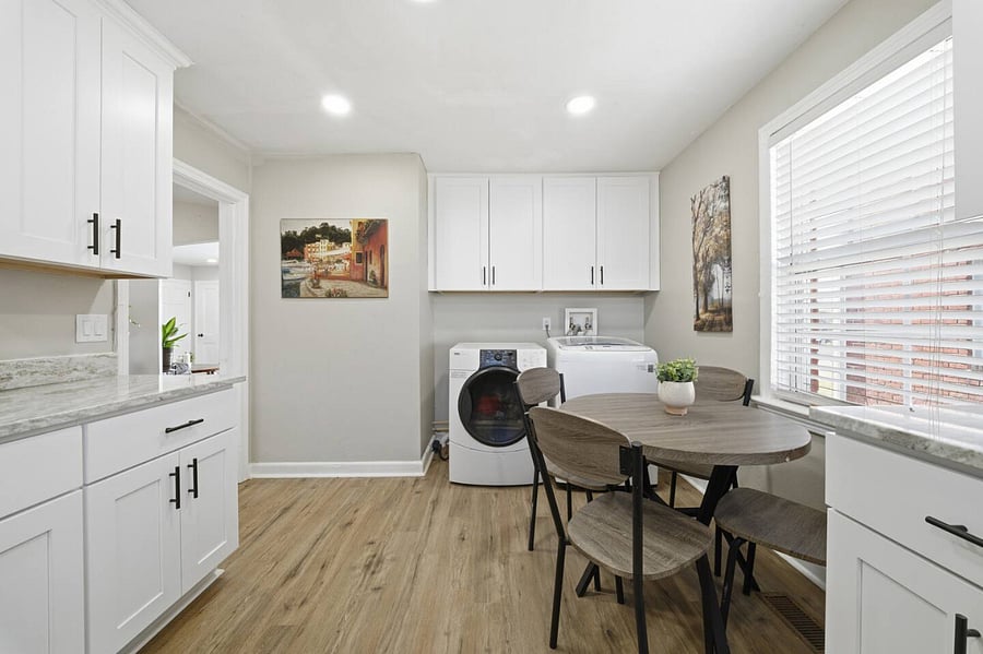 Sunny eat-in kitchen with a round table for four and plenty of natural light. Crisp white cabinetry, generous counter space, and in-unit laundry add comfort and convenience to your stay.