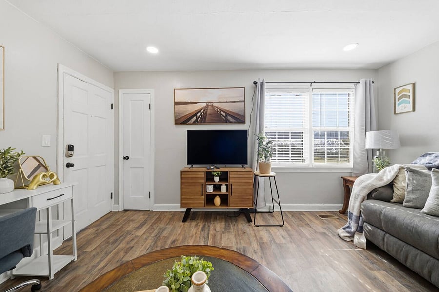 Bright and airy lounge with a large TV and sleek media console for easy streaming. Sunlit windows and soft accents add warmth, making it a comfortable spot to unwind after a day out.