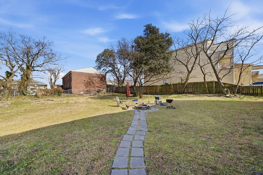 Spacious backyard with a paved walkway and open green space to enjoy the outdoors. A peaceful setting perfect for fresh air, relaxing afternoons, or spending time outside during your stay.