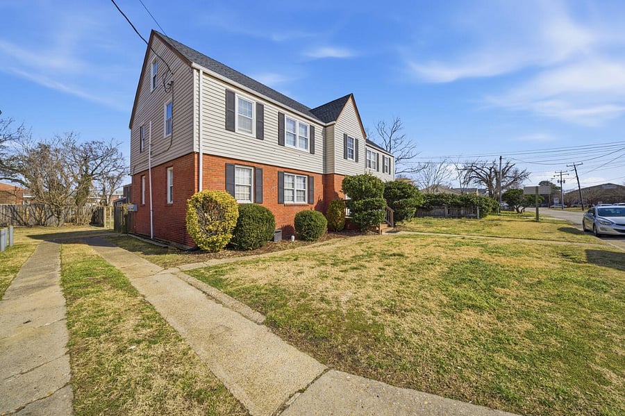Corner view of the home with a spacious yard and sidewalk access. Nestled in a quiet residential area, it offers easy arrivals and a comfortable neighborhood feel throughout your stay.