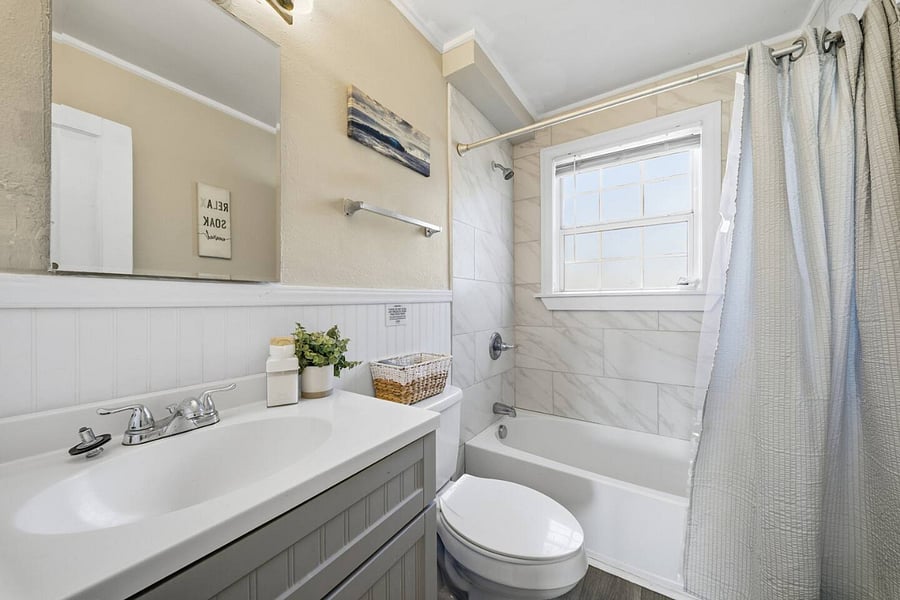 Clean and refreshed bathroom featuring a full tub and shower combo, bright vanity space, and fresh towels. Neutral finishes and natural light create a crisp, comfortable space to start and end your day.