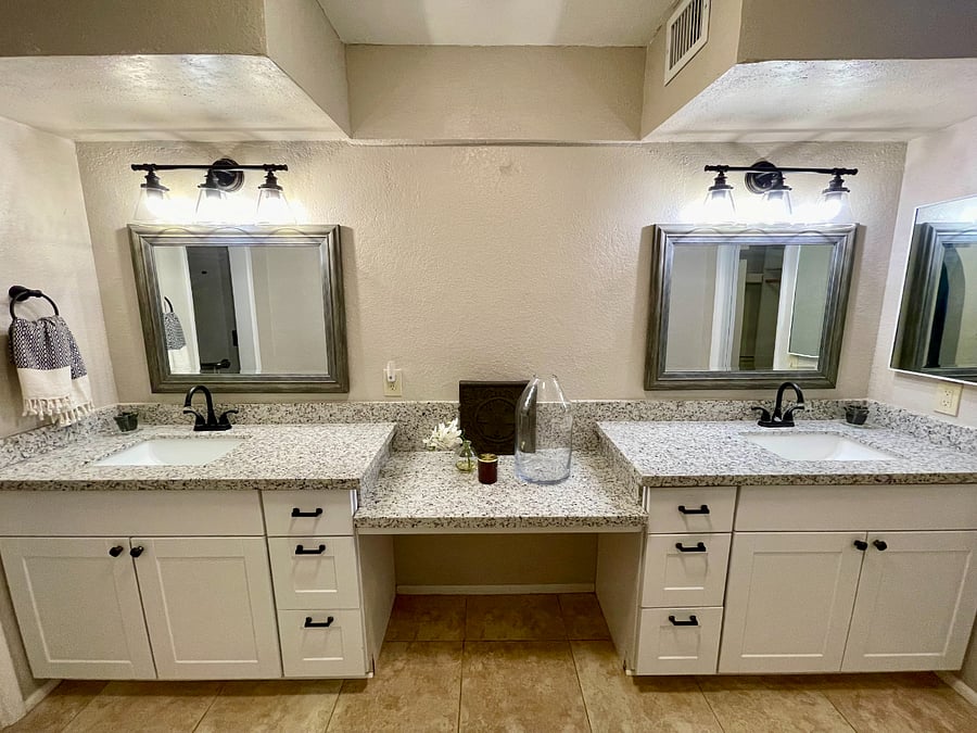 primary en suite bathroom with dual vanities & granite countertops