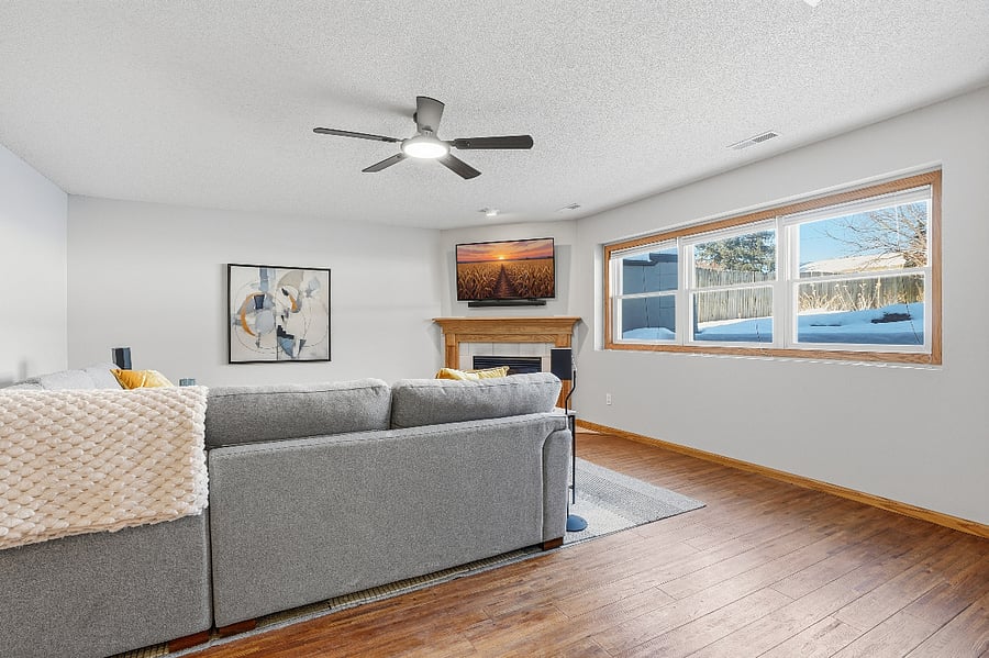 The lower level recreation room boasts a cozy fireplace and has a view of the backyard. It has been furnished with a brand new sectional couch and mounted new smart television.
