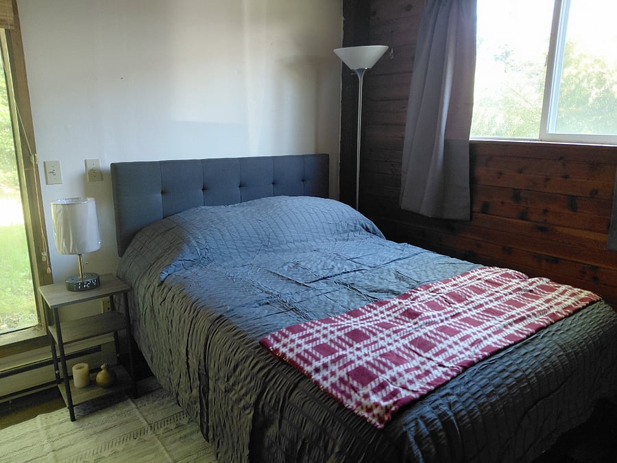 Bedside lamp has alarm clock and USB charging. Window view out to horse pasture.