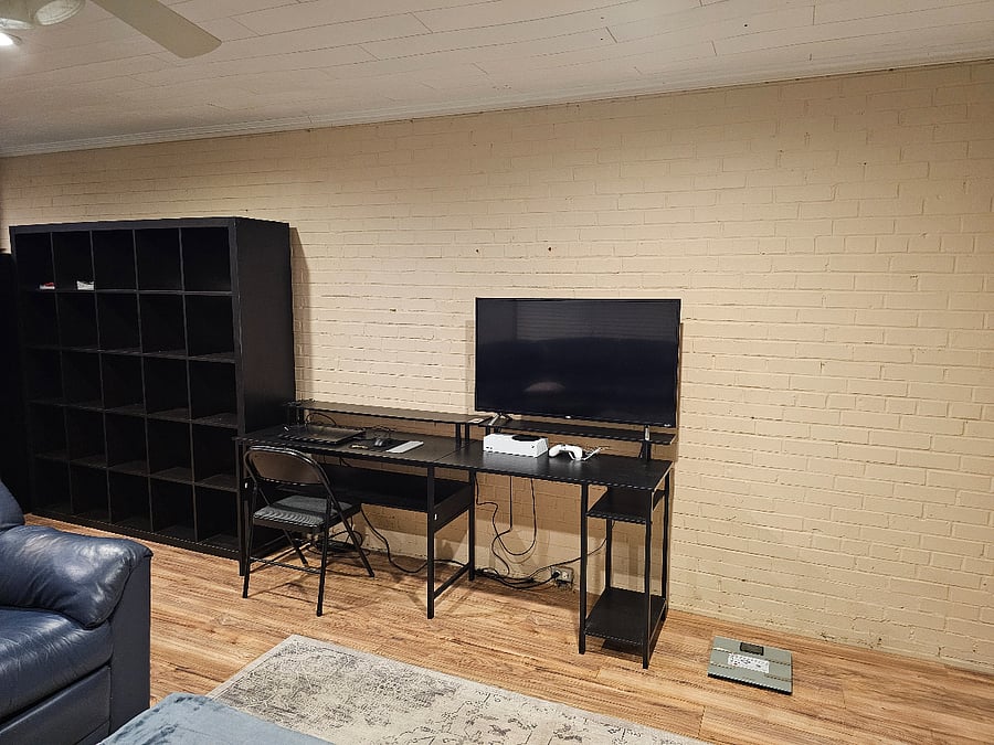 Smart TV, desk and bookcase in living room.