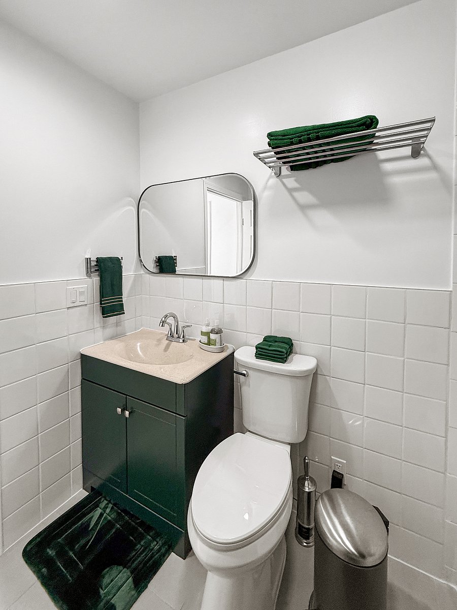 A compact, modern bathroom with tile walls, 