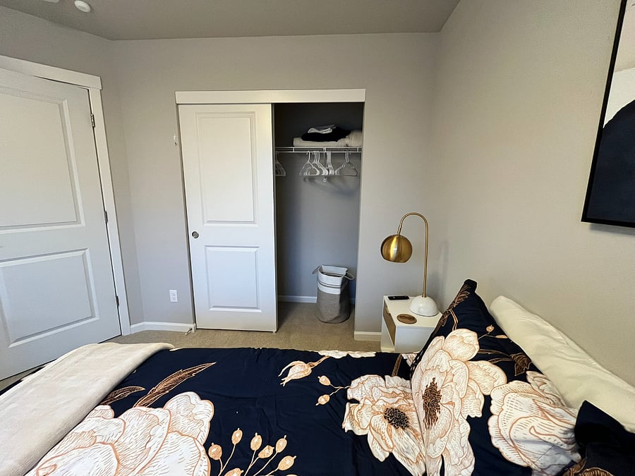 Closet has hangers and a clothes hamper plus a small portable chest of drawers for additional storage space.