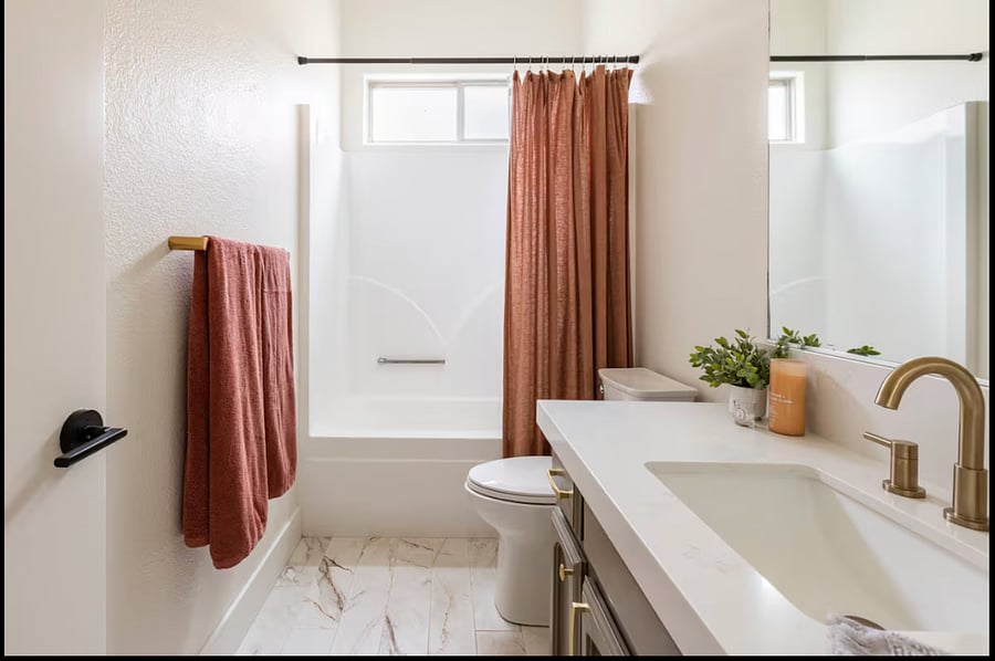 This is the tenants designated bathroom, featuring CB2 vanity lights, a bath/shower combo and ample storage. A custom gold mirror has recently been added, replacing the original builder-grade mirror shown.