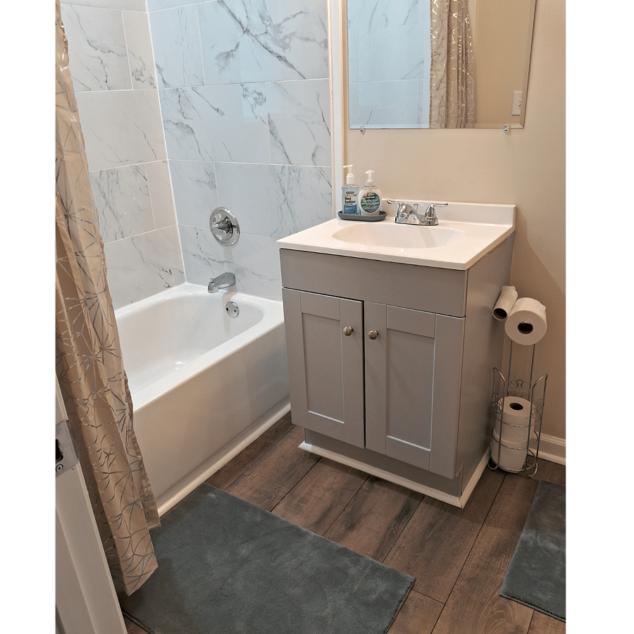 Fully tiled bathtub walls. Spacious vanity cabinet below sink.