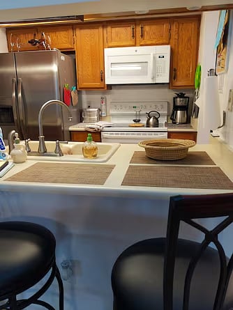 Galley Kitchen with side laundry room includes front loading washer and full size dryer. The kitchen is fully equipped with a microwave, electric cook top with oven, cooking utensils and dishwasher.
