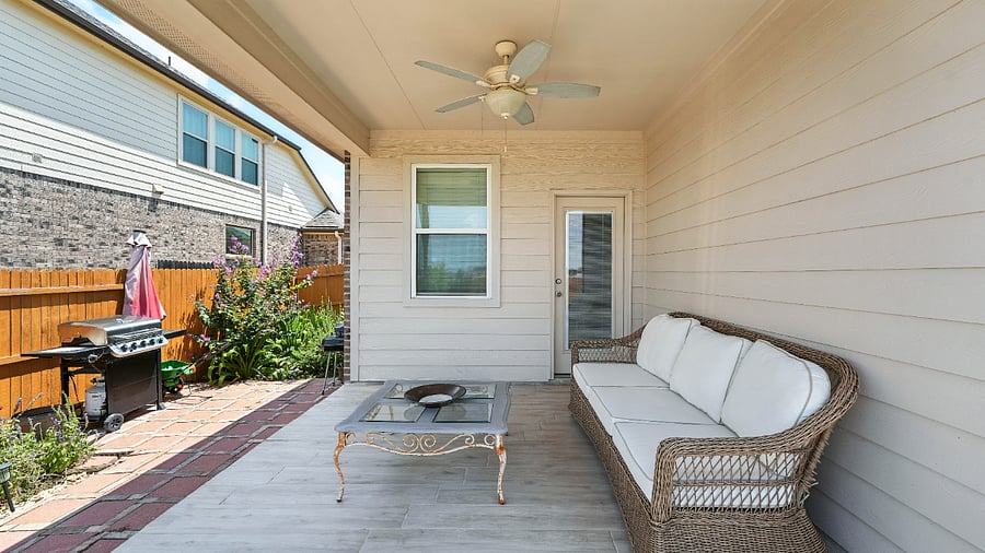 Covered back patio with ceiling fan and seatingideal for morning coffee, evening wind-downs, or casual outdoor meals.