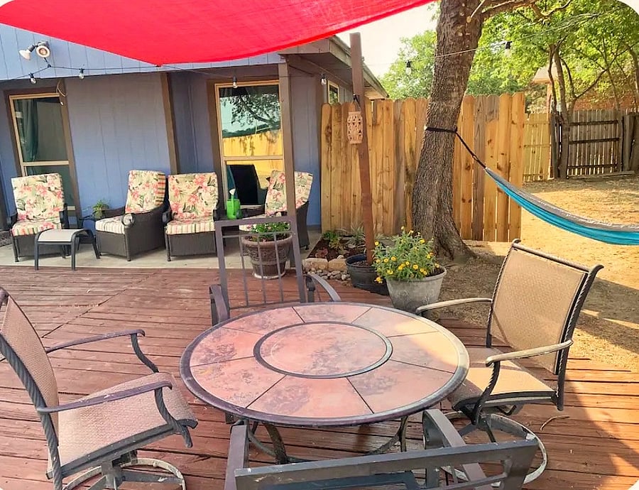 Spacious shaded backyard oasis with hammock, string lights, and dining deck perfect for Texas evenings, outdoor entertaining, and group gatherings