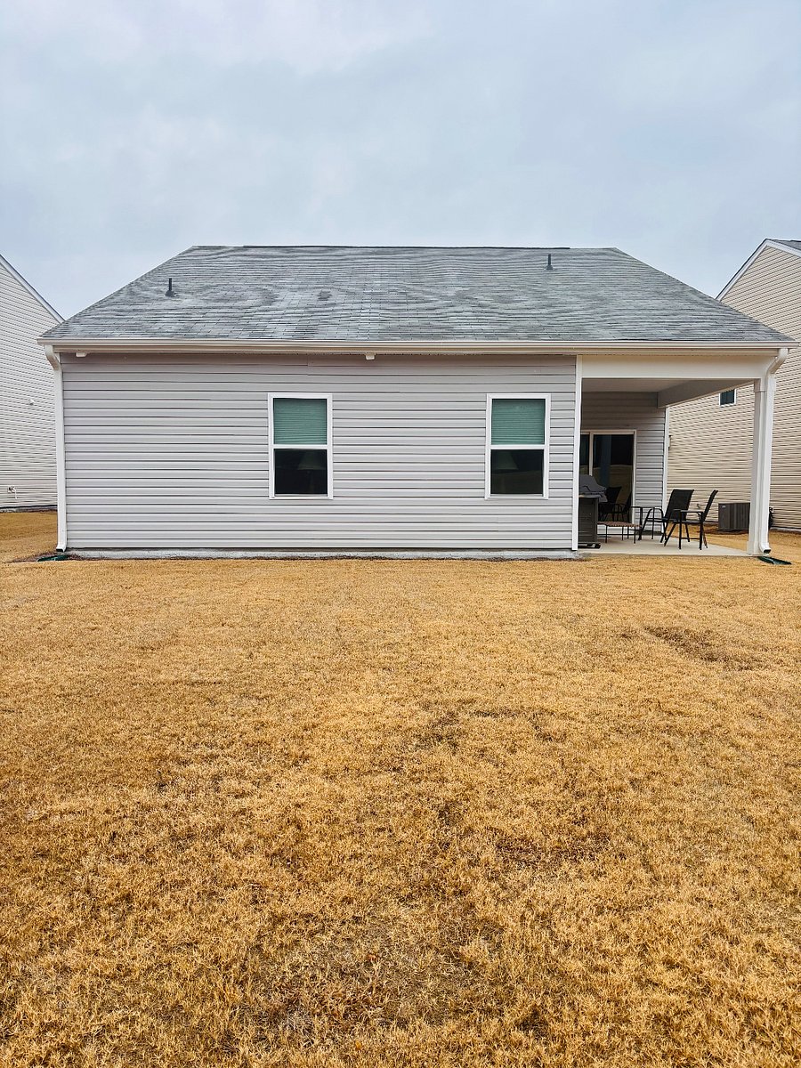Exterior back of our home with a covered patio and a large level back yard in which you are not responsible to maintain.