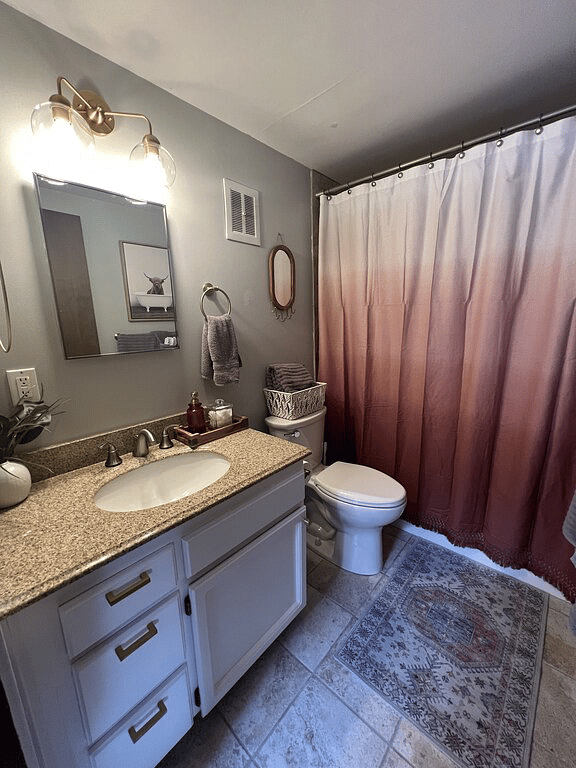 Main floor bathroom: tiled tub, quartz countertop, tall toilet.