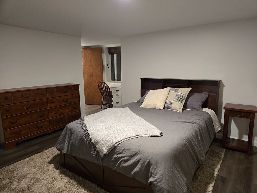 large size bedroom and fully furnished with large dresser, large mirror, side tables, headboard with storage, and a walk-in closet.