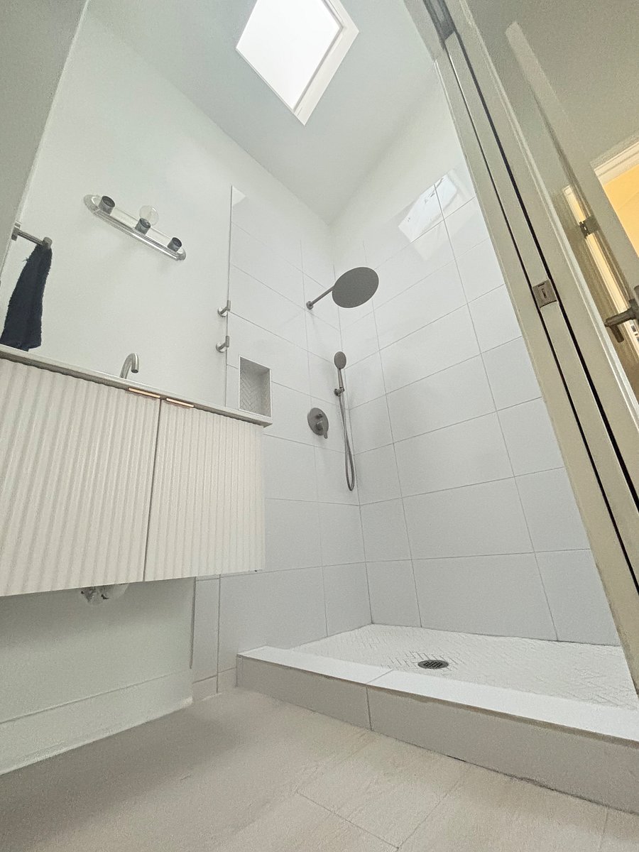 Modern, extra wide shower with rain head and handheld options. Skylight window brings in natural daylight.