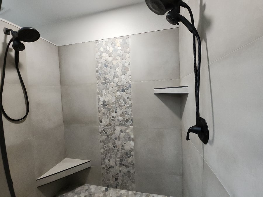 The ensuite bathroom has a walk-in shower with a stone pebble floor and wall tile waterfall, and dual shower heads create a spa-like ambiance. There are towel and robe hooks for easy access.