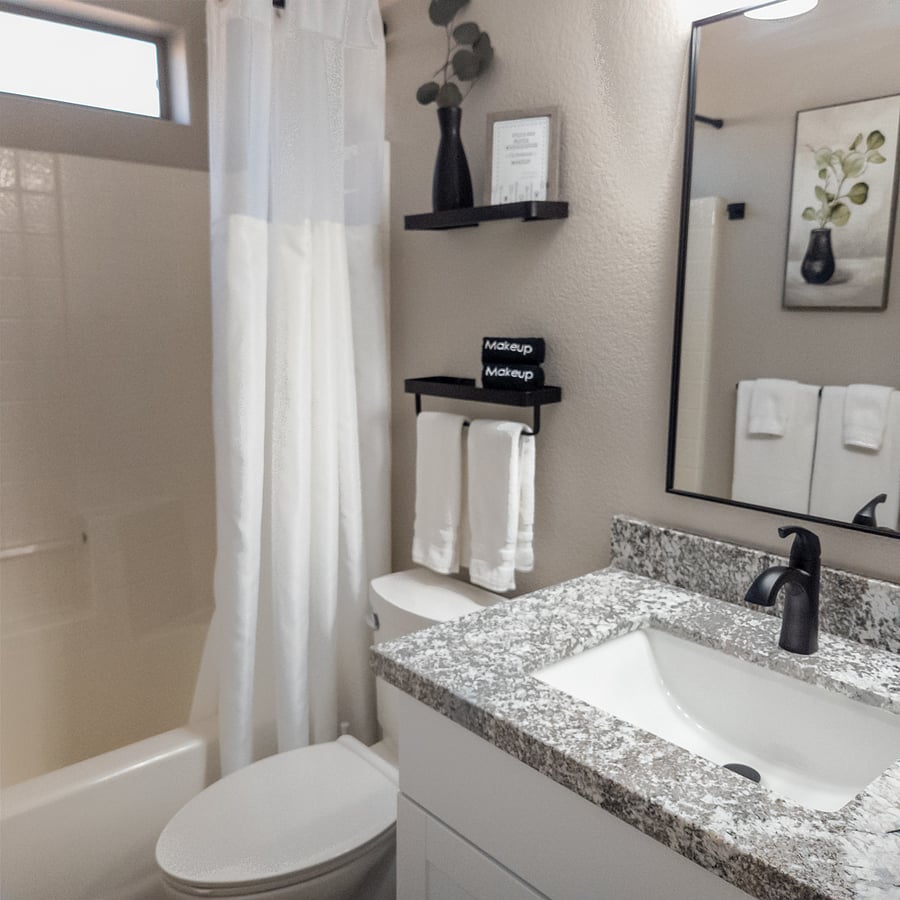Guest Oasis: bright and airy bathroom with granite counter vanity featuring shower/tub combo for relaxation.