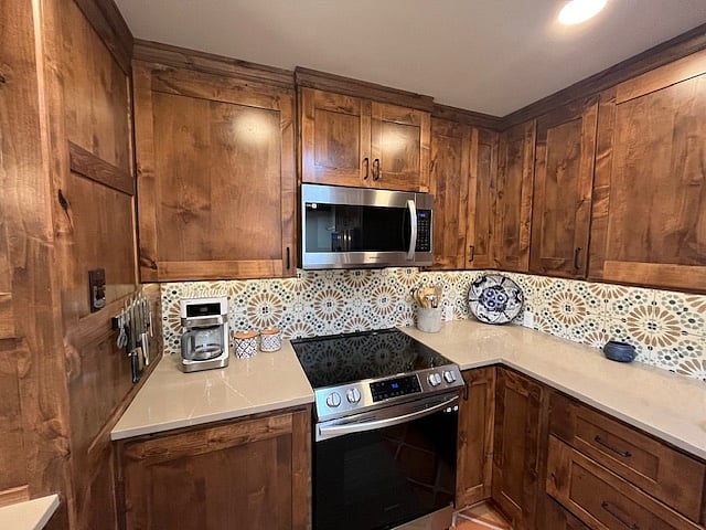 There is a full kitchen with many appliances, pots, pans, and a coffee maker. The refrigerator is full-sized with an ice maker.