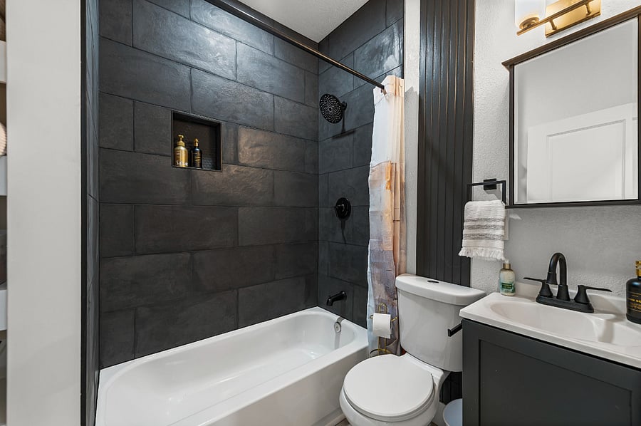 Step into the sleek hall bathroom featuring dramatic black tile, modern fixtures, and spa-inspired touches. With every detail thoughtfully designed, this space combines luxury and function, making your stay as comfortable as it is unforgettable.