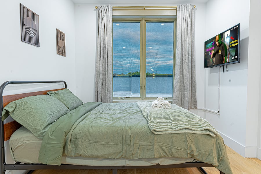 Bedroom with wall-mounted TVrelax after exploring Bushwick, Williamsburg, and Manhattan.