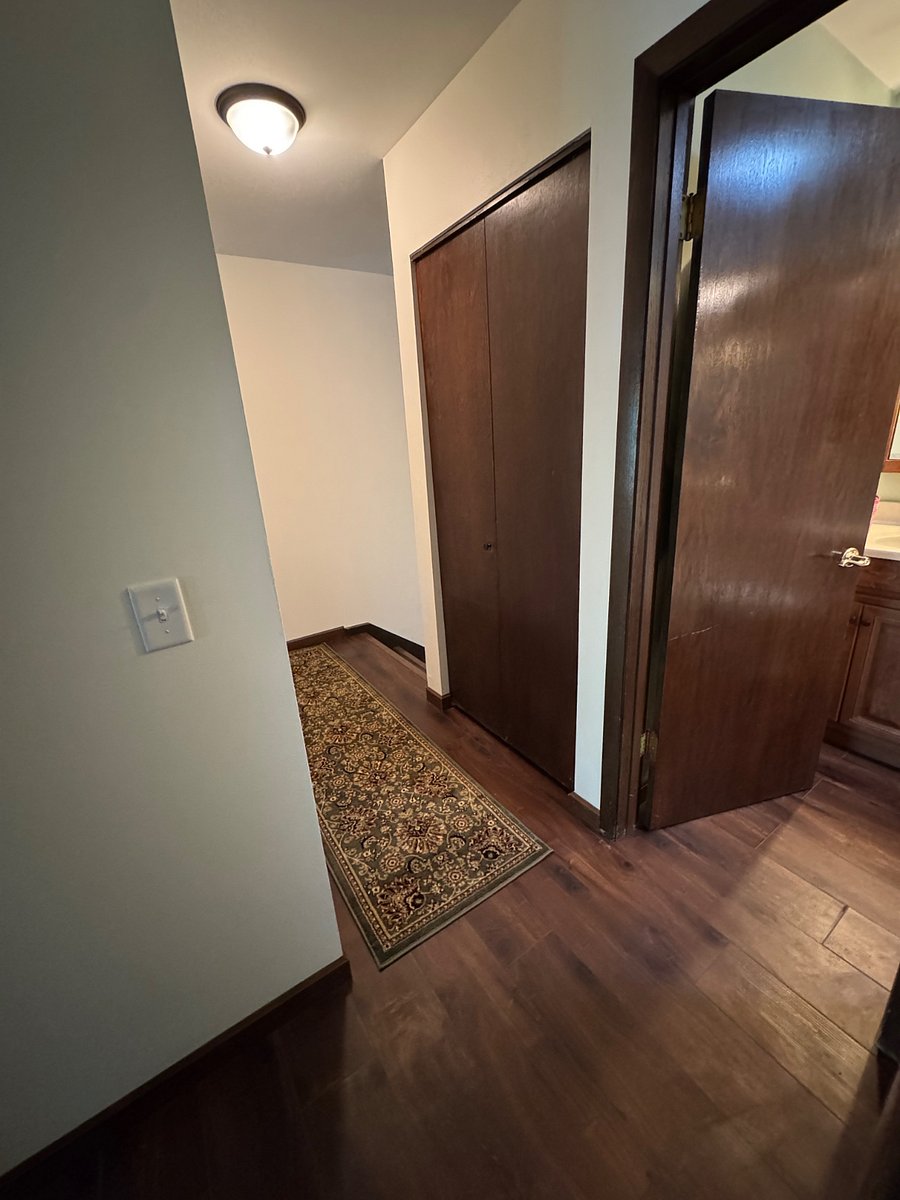Upstairs hallway. Bedroom door to left, bathroom on right, and stairs down to the lower living area.