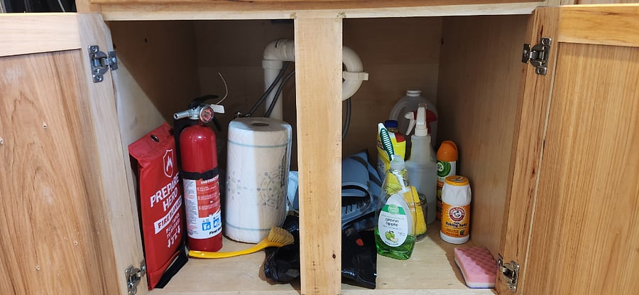 Under the Kitchen sink is a Fire Extinguisher and a Fire Blanker along with Cleaning Supplies.
