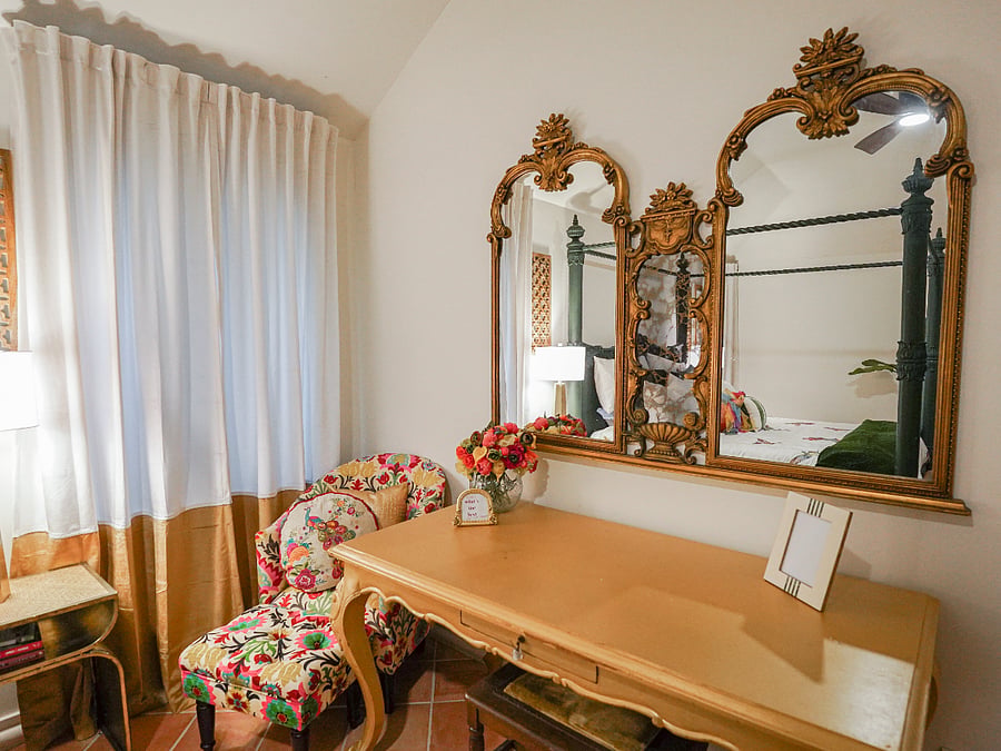 A full-size desk, elegantly painted in signature Ralph Lauren gold, invites focused work, while warm terracotta flooring grounds the space that is layered with a luxurious Ralph Lauren rug and a textured raw hide overlay for an added touch of authentic warmth and timeless ranch sophistication.
An elegant mirrored faux fireplace crowned by a 55" mounted smart TV adds refined ambiance. Velvet curtains frame the windows alongside modern blinds for perfect light control, with both an outdoor private entrance and indoor access for ultimate convenience for privacy all secured by smart keyless entry.