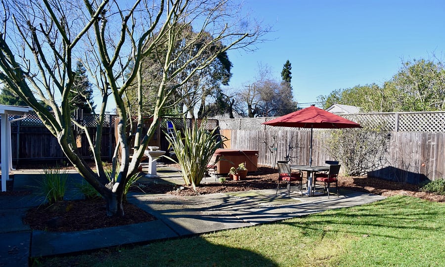 Large back yard with hot tub, patios, lawn and table