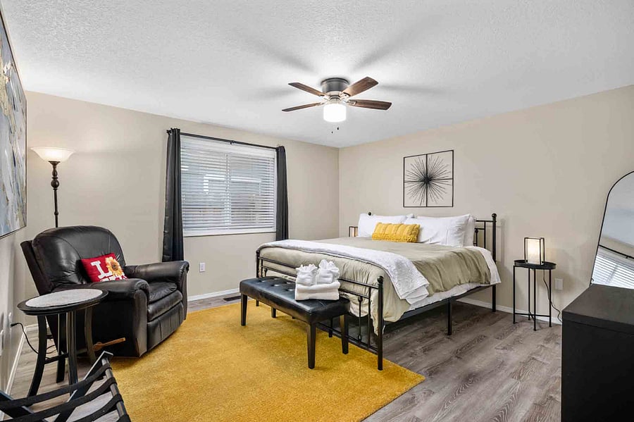The primary bedroom offers a peaceful retreat with a king bed, reading area, large walk in closet, and an attached bathroom with shower.