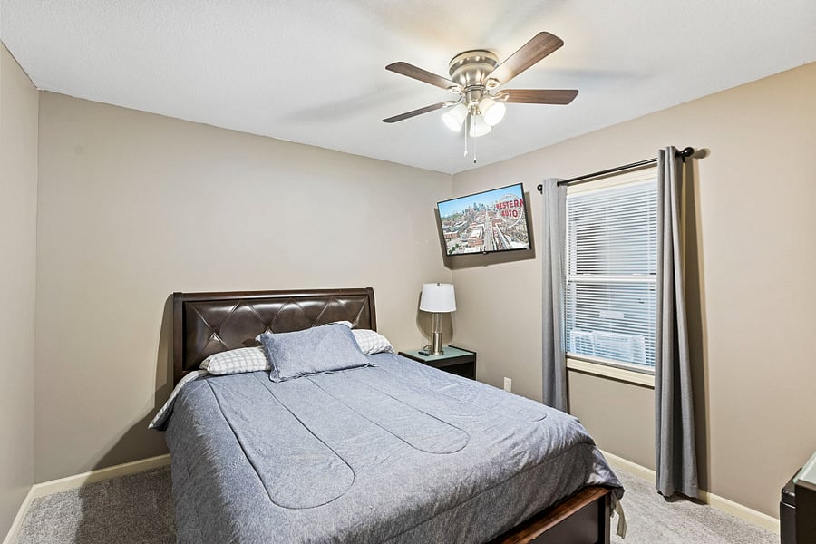 Well-appointed bedroom with Smart TV, nightstand, lamp, and dresser for convenient storage