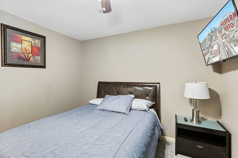 Well-appointed bedroom with Smart TV, nightstand, lamp, and dresser for convenient storage