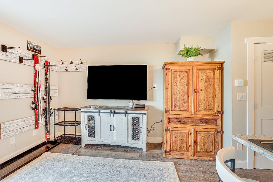 Custom hooks and ski rack, smart TV, and armoire in living room.