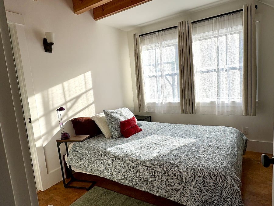 Bedroom has blackout curtains and a window air conditioner for hot summers.