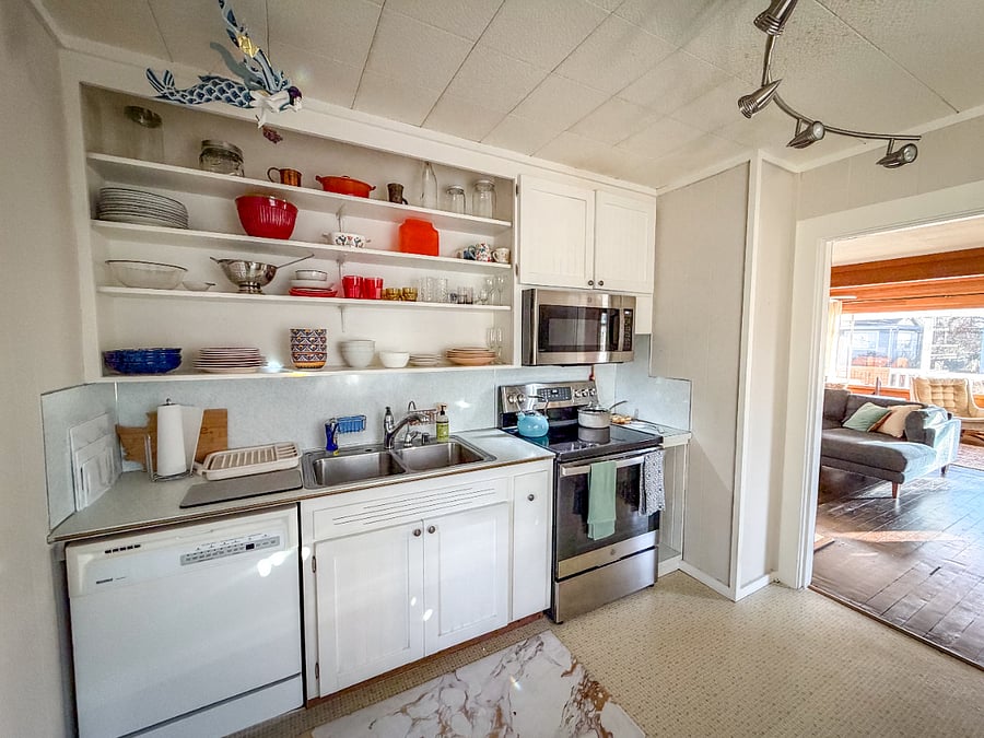 Fully equipped kitchen with open shelving and updated appliances.