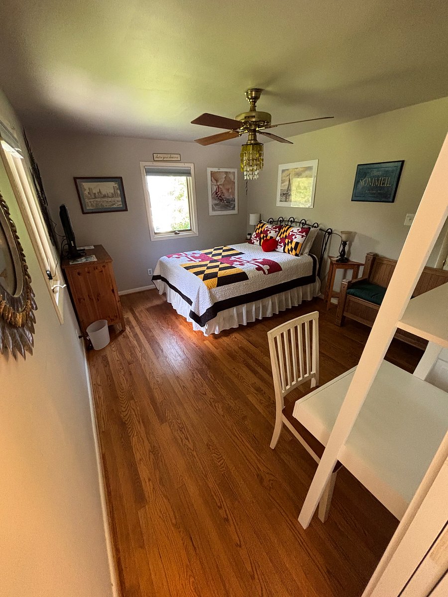 This photo shows entering the bedroom with a desk and shelf unit on the right dresser on the left and the queen size bed also shows the casement window with pulldown screen and blackout shade and hardwood solid oak flooring.