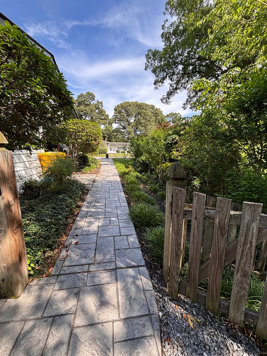 This photo shows the Paved sidewalk leading from the driveway through the fence gate to the back patio area