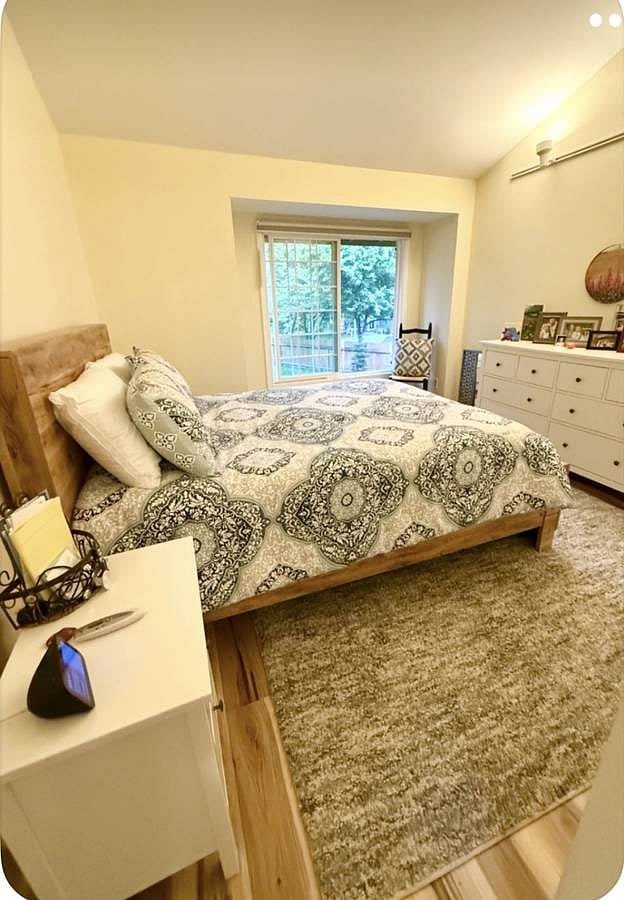 primary bedroom with queen bed, dresser, & large window with mountain views- vaulted ceiling