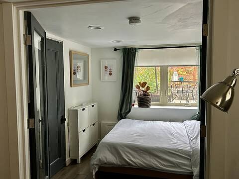 Primary bedroom includes closet, big windows, and queen bed. Shades and blackout curtains allow for restful sleep.
