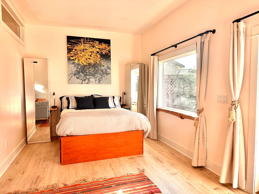 Queen sized bed beside picture window looking out on the garden.  Custom good sized closets with drawers and racks for hanging clothes.