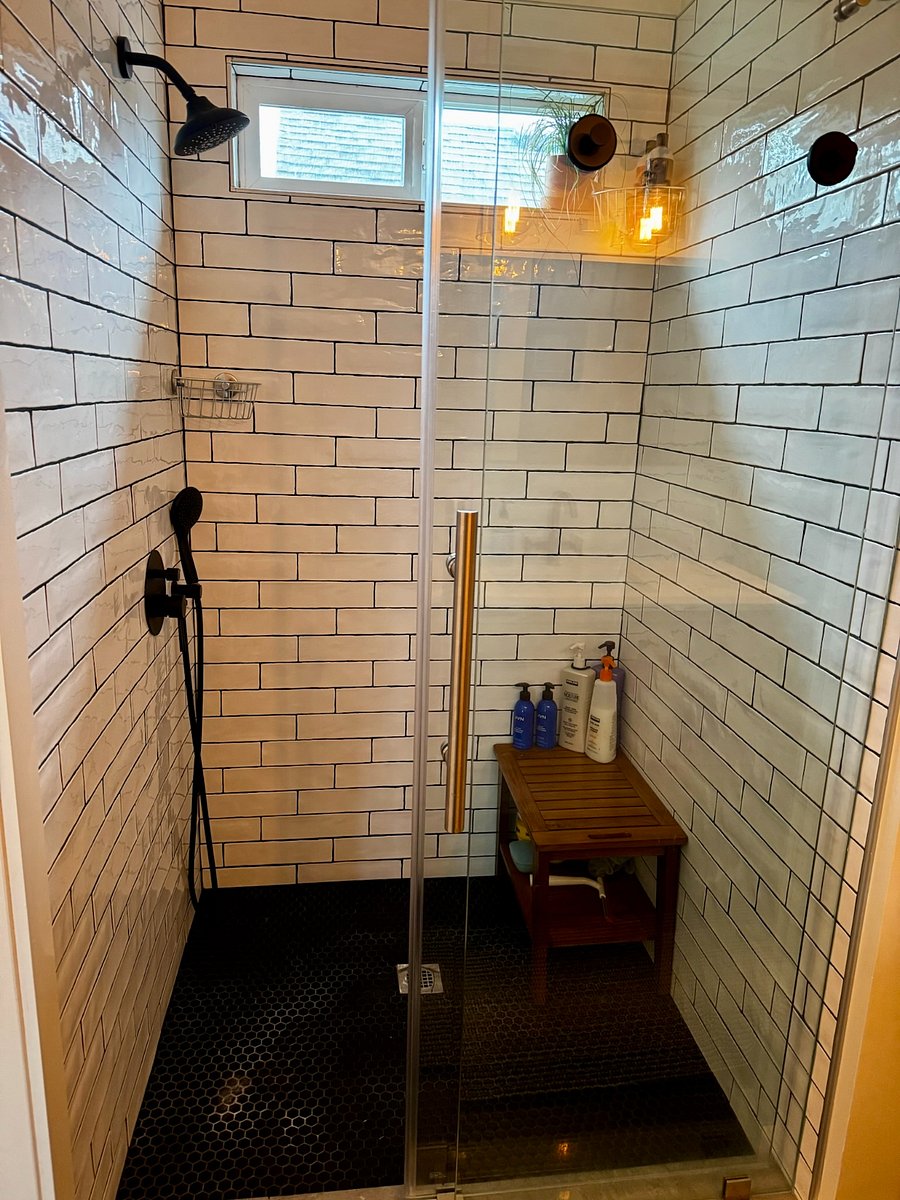 Spa-like bathroom with a huge walk-in shower and endless on-demand hot wateryoull never run out. Enjoy the rain shower head with strong water pressure, a cozy built-in bench for relaxing with the handheld sprayer, and beautiful natural light from the valance window. Thoughtfully designed lighting by a local Portland-based renovation company completes the space.
