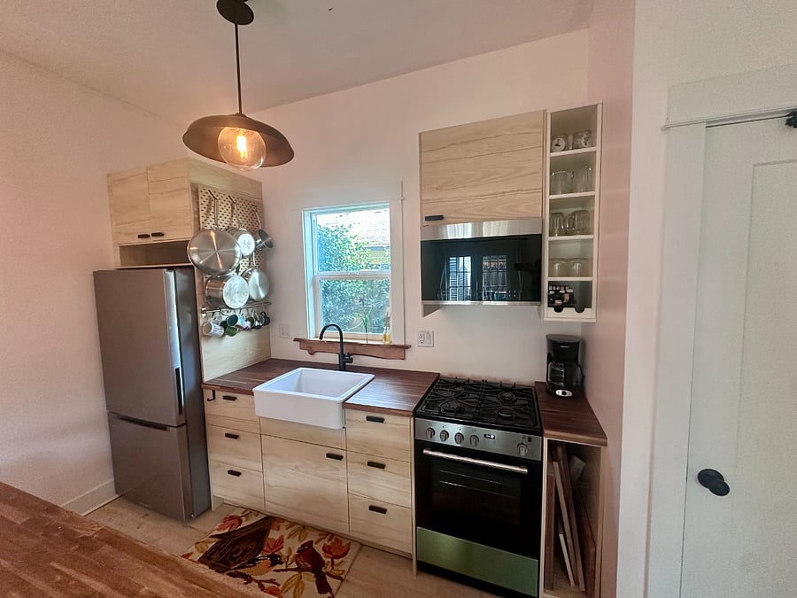 Scandinavian inspired kitchen with gas range stove, oven, microwave and sink disposal.