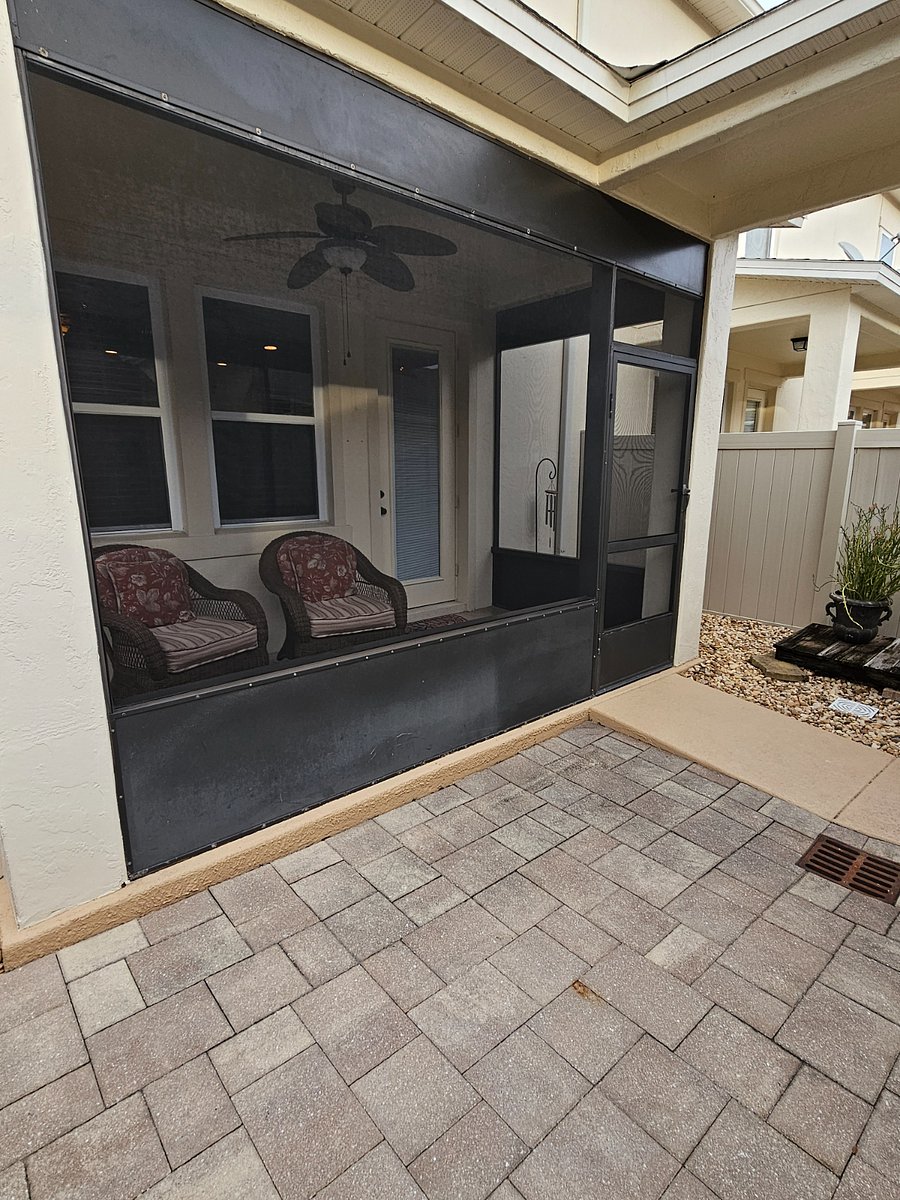 Outside screened porch with comfortable furniture, overlooking courtyard with grill.