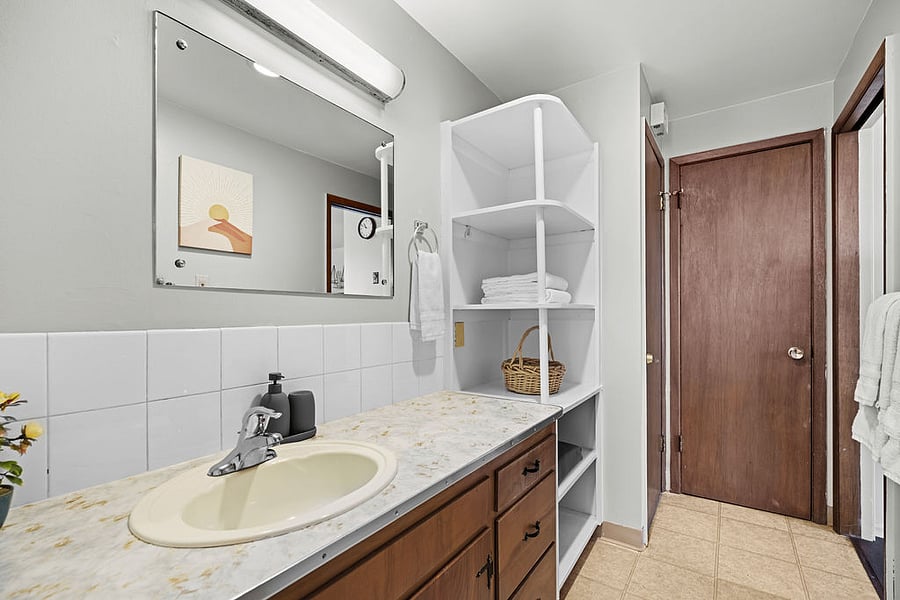 Bathroom closet includes hangers, a laundry basket, broom, and dustpan.
