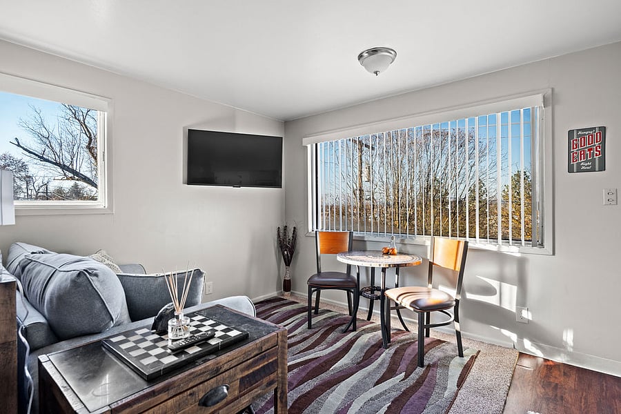 Cozy living room with city views, a love seat, 43" Fire TV, 2-seater bistro dining table, and an end table with local historical books for added regional charm.