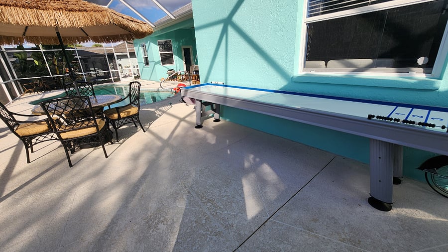 Solar lighting built in to the tiki umbrella with comfortable coastal outdoor dining table and outdoor shuffleboard table.